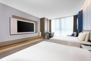 a hotel room with two beds and a flat screen tv at Atour Hotel Jinan West Railway Station in Jinan +60 photos