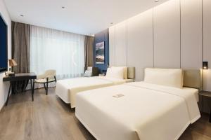 a hotel room with two beds and a desk at Atour Hotel Dalian Airport in Dalian