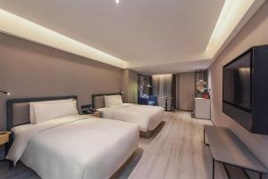 重慶市にあるAtour S Hotel Chongqing Jiefangbei Hongyadong Riverviewのベッド2台、薄型テレビが備わるホテルルームです。