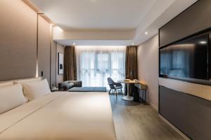 蘇州市にあるAtour Hotel Suzhou Guanqian Streetのベッド1台、薄型テレビが備わるホテルルームです。