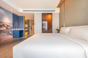 a bedroom with a large white bed and a bathroom at Atour Hotel Xiamen Lianban Mingfa Plaza in Xiamen