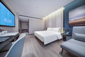 長沙市にあるAtour Hotel Changsha Dongtangのベッドとテレビ付きのホテルルーム