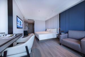 a hotel room with a bed and a couch at Atour X Hotel Ningbo Railway Station Liuting Street in Ningbo