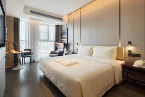 Atour Hotel Chongqing Qibo Center في تشونغتشينغ: غرفة نوم مع سرير أبيض كبير ومكتب
