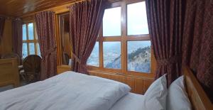 a bedroom with a bed and a large window at Kashmir Eagle Heights Cottage & Restaurant by LMC in Muzaffarabad