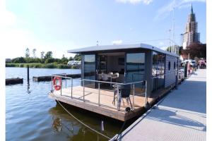 石勒苏益格Hausboot Fjord Aries mit Dachterrasse in Schleswig的停泊在水面码头的船屋