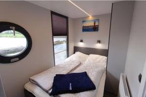 a small bedroom with a bed with a window at Hausboot Fjord Aries mit Dachterrasse in Schleswig in Schleswig