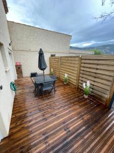 a wooden deck with a table and an umbrella at Luxury spa vallon in Vallon-Pont-dʼArc