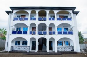 a white building with blue windows and a balcony at Becky Best Apartments in Limbe