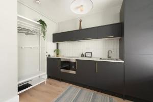 a kitchen with black cabinets and a sink at The CoDalston in London
