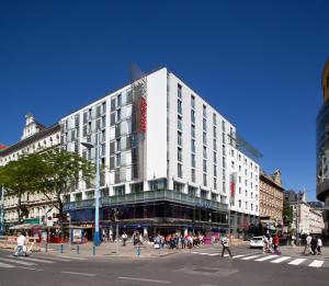 a large white building on a busy city street at IntercityHotel Wien in Vienna