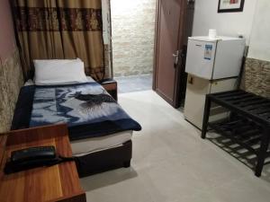 Zimmer mit einem Bett, einem Tisch und einem Kühlschrank in der Unterkunft Amman Palace Hotel in Amman