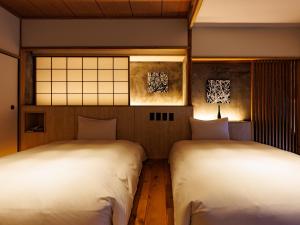 2 Betten in einem Zimmer mit weißer Bettwäsche in der Unterkunft Kurofune Hotel in Shimoda