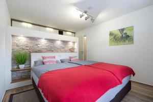 a bedroom with a red bed and a brick wall at Glückspilz in Obermaiselstein