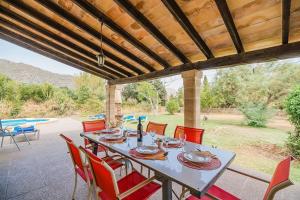 - une table à manger avec des chaises rouges sur la terrasse dans l'établissement Villa Can Sureda, à Pollença