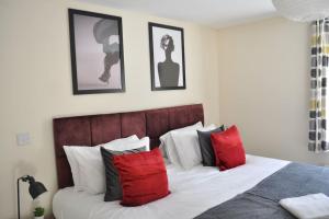 スウィンドンにあるBeaney View House - Modern, Spacious 4 Bedrooms Ensuites House with Free Wifi and Parkingsのベッドルーム1室(赤と白の枕が備わるベッド1台付)