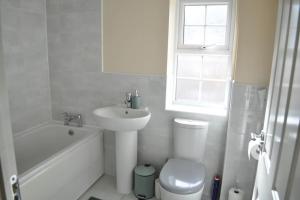 a white bathroom with a sink toilet and a window at Beaney View House - Modern, Spacious 4 Bedrooms Ensuites House with Free Wifi and Parkings in Swindon