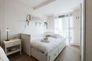 a white bedroom with a large bed and a window at Appartement in Zeeland - Kabbelaarsbank 512 - Port Marina Zélande - Ouddorp - With garage - not for companies in Ouddorp