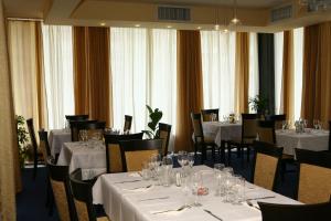 ein Esszimmer mit weißen Tischen und Stühlen und Fenstern in der Unterkunft Hotel Queen in Aydemir