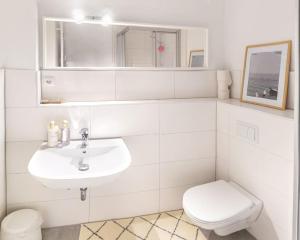 La salle de bains blanche est pourvue d'un lavabo et de toilettes. dans l'établissement City-Appartement, Holtenauer Straße mit 24h Check-in, à Kiel