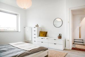 a white bedroom with a bed and a mirror at City-Appartement, Holtenauer Straße mit 24h Check-in in Kiel