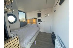 1 dormitorio con 1 cama en una habitación con ventana en Hausboot Fjord Ankerplatz mit Biosauna in Schleswig, en Schleswig