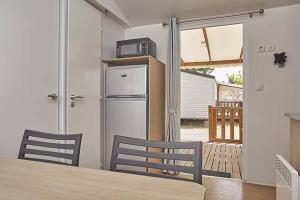 eine Küche mit einem Tisch, 2 Stühlen und einem Kühlschrank in der Unterkunft La petite Camargue in Le Grau-du-Roi