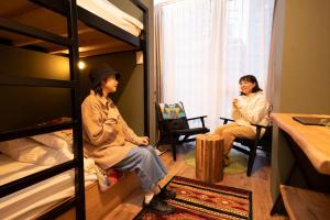 two women sitting in a room with bunk beds at Glamping Tokyo Asakusa in Tokyo