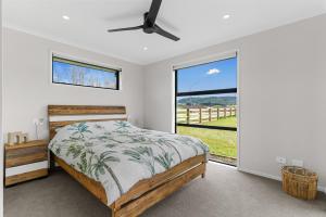 ein Schlafzimmer mit einem Bett und einem großen Fenster in der Unterkunft Sweet and Stylish - Mangawhai Heads Holiday Home in Mangawhai