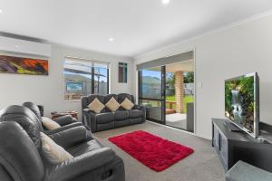 a living room with two couches and a flat screen tv at Summertime Bliss - Mangawhai Heads Holiday Home in Mangawhai