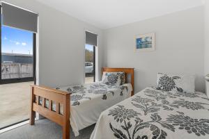 1 dormitorio con 2 camas y balcón en Summertime Bliss - Mangawhai Heads Holiday Home, en Mangawhai