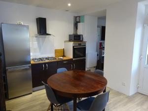 uma cozinha com uma mesa de madeira e uma cozinha com um frigorífico em Gîte des Pleiades em Villemoirieu