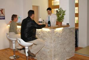 tres personas sentadas en un bar con un camarero en Sportház en Gyenesdiás