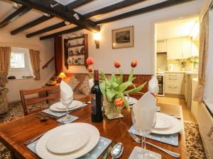 a dining room table with plates and flowers on it at Sycamore Cottage in Hucklow