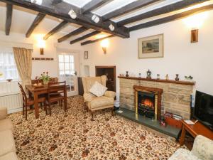 a living room with a fireplace and a table at Sycamore Cottage in Hucklow