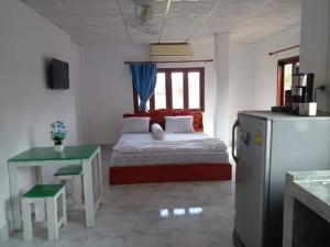 a bedroom with a bed and a table and a refrigerator at Ban Saylomleng Residence in Vientiane