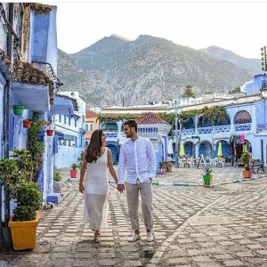 a man and a woman walking down a street at DAR Casa Plasa Grande CHEFCHAOUEN in Chefchaouene