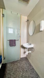 uma casa de banho com um lavatório e um chuveiro com um espelho. em Hotel Lavender Inn em Malaca