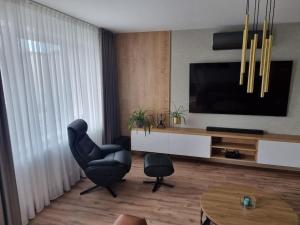 Sala de estar con silla negra y TV en Krásný apartman s vybavením a bezplatným parkovanim, en Banská Bystrica