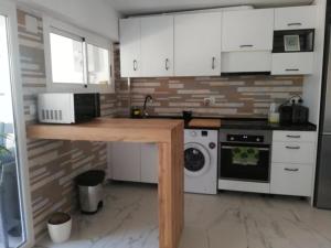 a kitchen with white cabinets and a washer and dryer at Sunny 3 bed beach flat - large terrace with sea view in Puerto de Sagunto