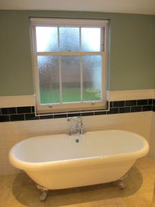 a bath tub in a bathroom with a window at Acorn Chapel - Beautiful Converted Chapel in Norwich