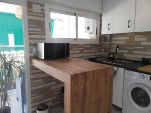 una cocina con microondas en una encimera de madera en Sunny 3 bed beach flat - large terrace with sea view en Puerto de Sagunto