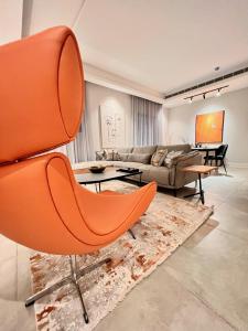an orange chair in a living room with a couch at Cadee Living - Al Nakheel in Riyadh