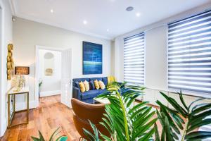 a living room with a blue couch and a plant at Hybrid Resi - Battersea in London