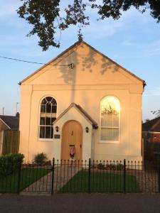 uma igreja branca com uma cerca em frente em Acorn Chapel - Beautiful Converted Chapel em Norwich