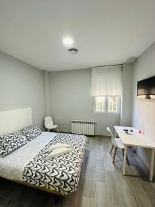 - une chambre avec un lit, une table et un bureau dans l'établissement HOSPEDAJE CUATRO VIENTOS, à Madrid