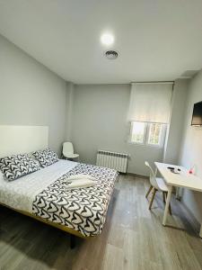 HOSPEDAJE CUATRO VIENTOS في مدريد: غرفة نوم بسرير وطاولة ومكتب