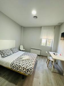 1 dormitorio con cama, mesa y escritorio en HOSPEDAJE CUATRO VIENTOS, en Madrid