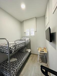 a small room with two bunk beds and a table at HOSPEDAJE CUATRO VIENTOS in Madrid