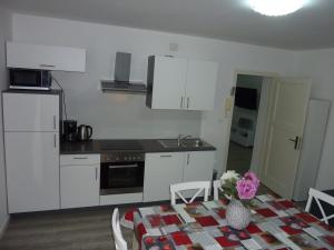 a kitchen with white cabinets and a table with flowers on it at APARTMENT KAYA in Zadar